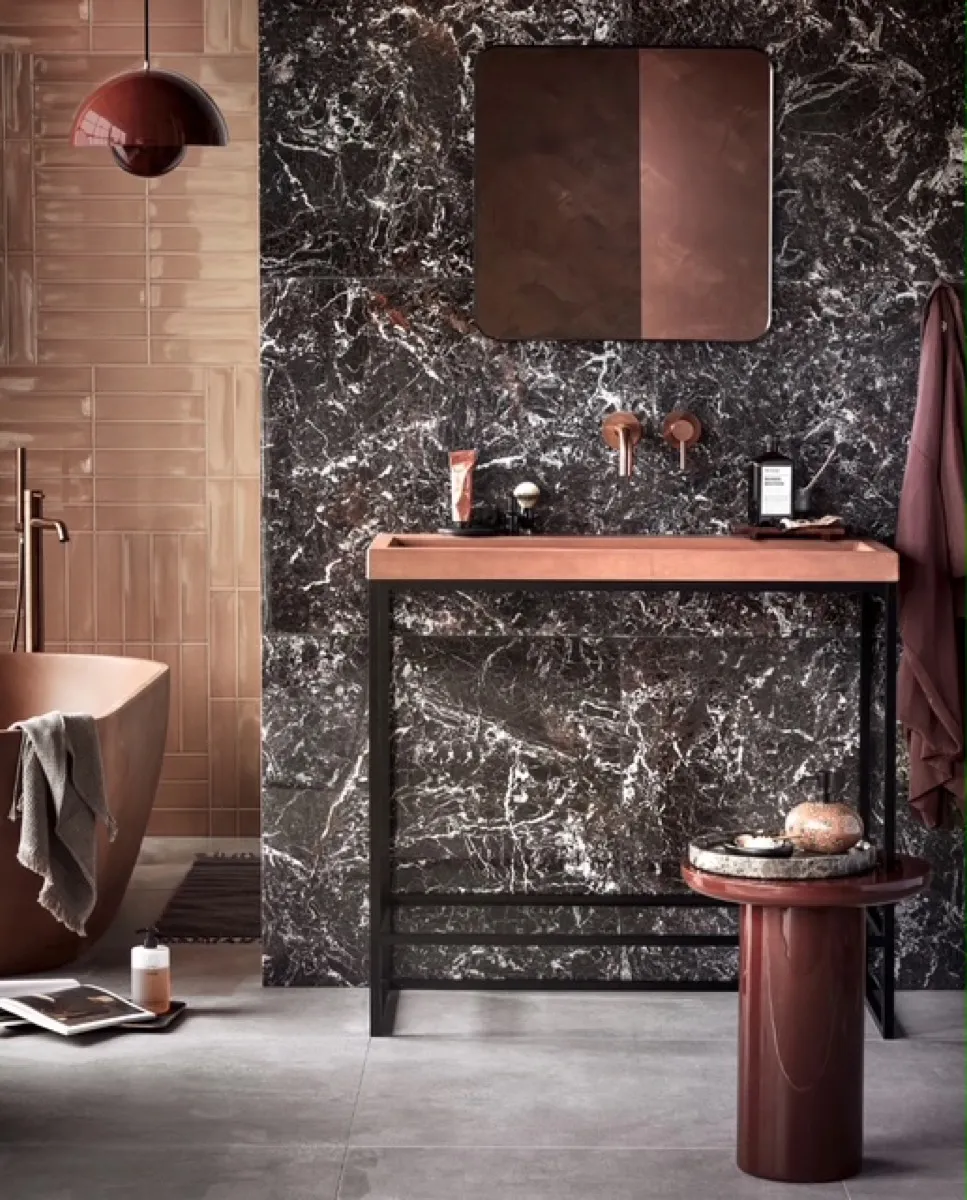 Badkamer met zwart marmer, terracotta tegels en een koperen wastafelblad.