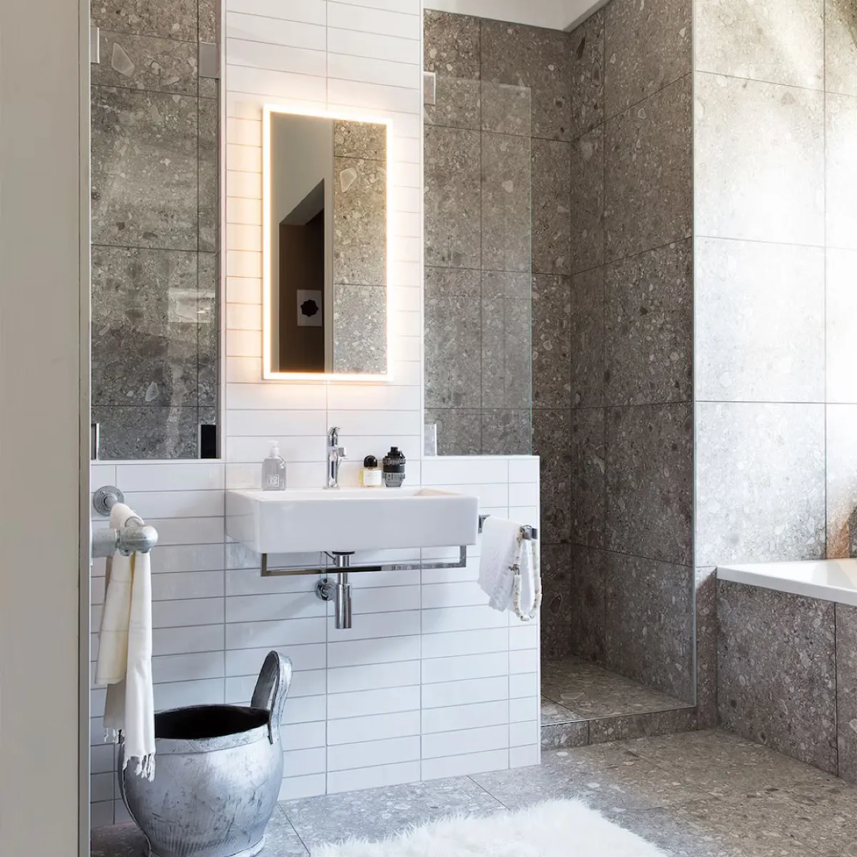 Strakke badkamer met natuursteenlook, zwevende wastafel en inloopdouche.
