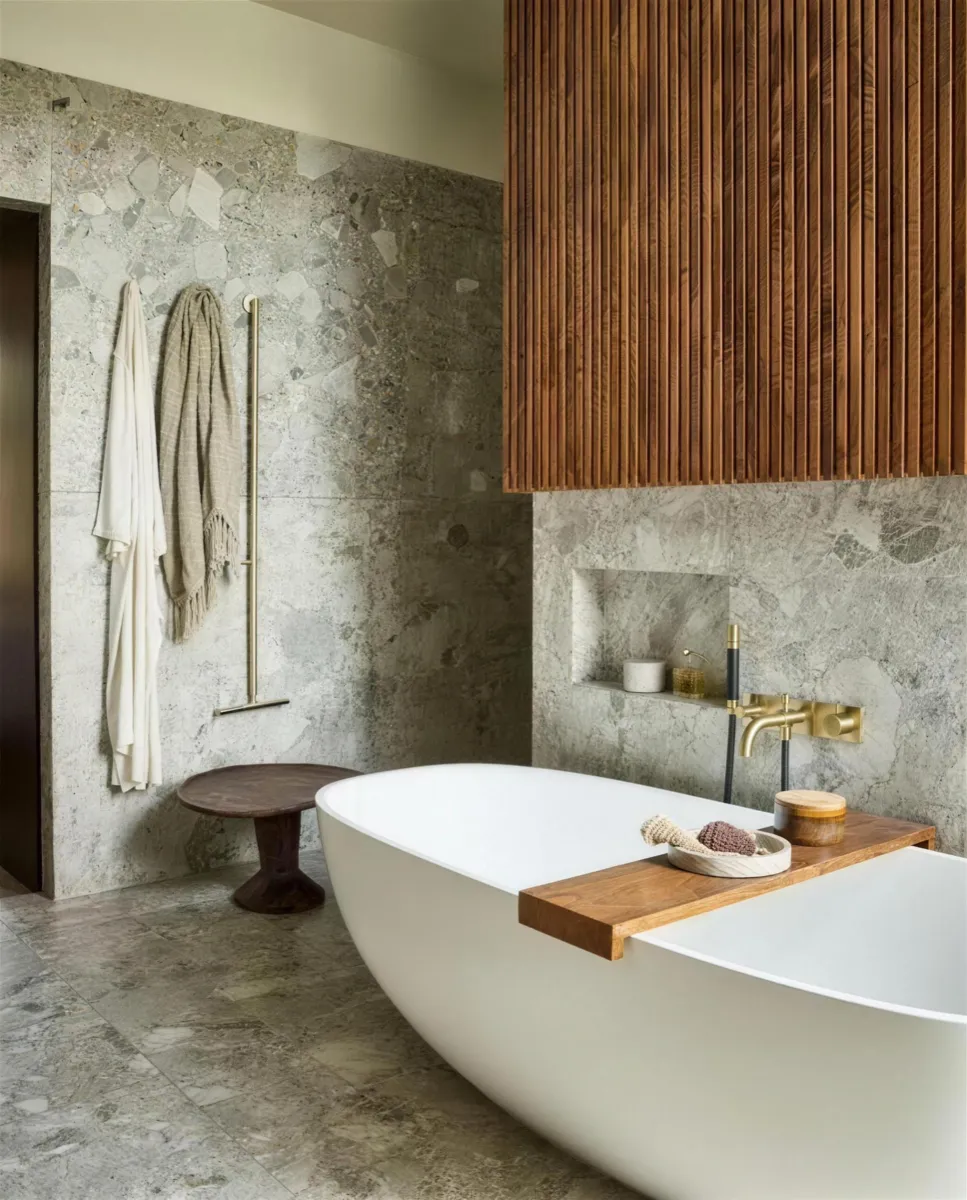 Spa-badkamer met vrijstaand bad, natuursteen en een houten lamellenwand.