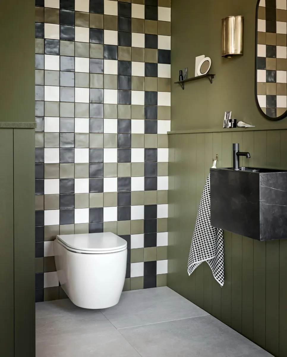 Gastentoilet met groene lambrisering en handgevormde tegels.