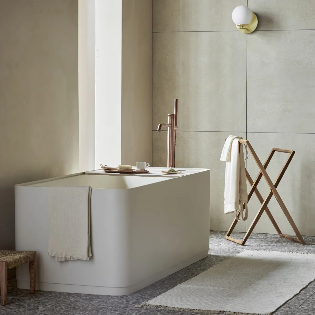 Badkamer met betonlook wanden en een vrijstaand bad.